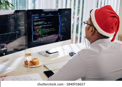 Young Indian Software Developer In Santa Hat Working In Office On Christmas Eve