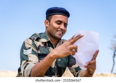 Young Indian Soldier Reading Letter Or Mail From Family Member While At Service On Top Of Mountian - Concept Of Missing Family, Bonding And Distant Communication