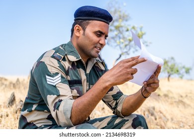 Young Indian Soldier Reading Letter Or Mail From Family Member While At Service On Top Of Mountian - Concept Of Missing Family, Bonding And Distant Communication