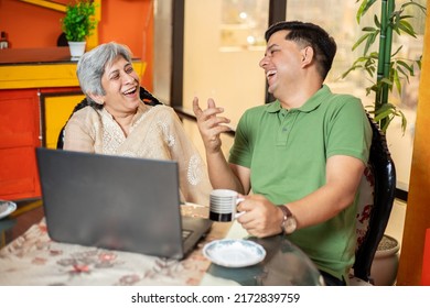 Young Indian Son And Old Mother Laughing And Using Laptop Or Watching Movie Together, Younger Generation Spend Time With Senior Citizen , Entertainment And Fun At Home.