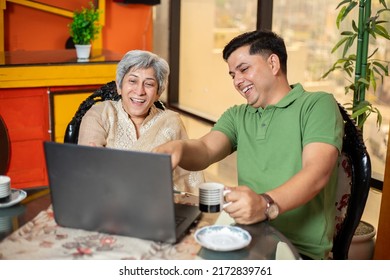 Young Indian Son And Old Mother Using Laptop Together. Younger Generation Teaching Senior People How To Use Computer. Asian Family Using Internet Or Web Surfing At Home.