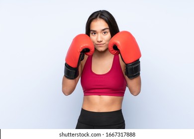 Young Indian sport woman isolated on blue background with boxing gloves