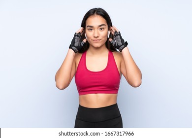 Young Indian sport woman isolated on blue background listening music and looking to the front