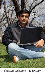 Young Indian Student Working On His Laptop Outside The College Campus.