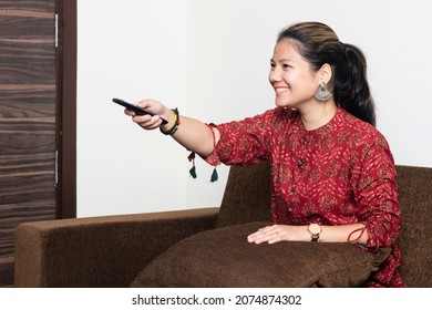 Young Indian Watching Television While Relaxing On The Couch. Young Millennial Girl Relaxing On Weekends. Rest From Work, Having Fun, Social Media And Over The Top Services Concept.