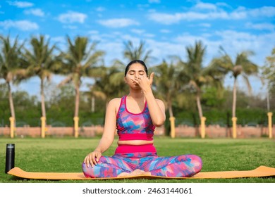 young indian woman doing Anulom Vilom Pranayama yoga pose in garden. sports, workout, meditation, well being, mental health, international yoga day concept. - Powered by Shutterstock