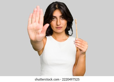 Young Indian woman holding a toothbrush isolated standing with outstretched hand showing stop sign, preventing you. - Powered by Shutterstock