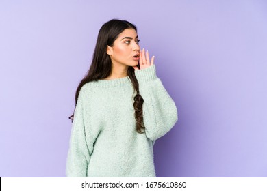 Young indian woman isolated on purple background is saying a secret hot braking news and looking aside - Shutterstock ID 1675610860