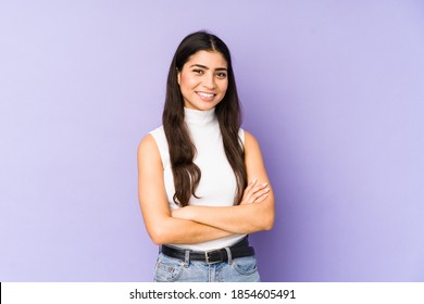 Young indian woman isolated on purple background who feels confident, crossing arms with determination.
