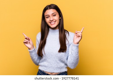 Young Indian woman isolated on yellow background pointing to different copy spaces, choosing one of them, showing with finger.