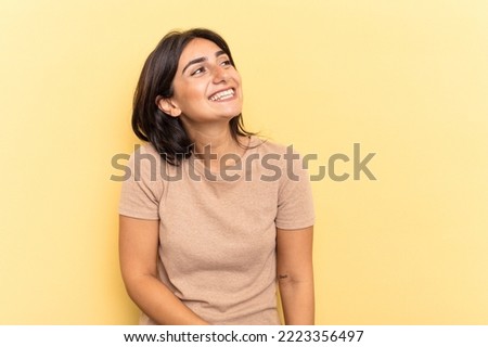 Young Indian woman isolated on yellow background relaxed and happy laughing, neck stretched showing teeth.