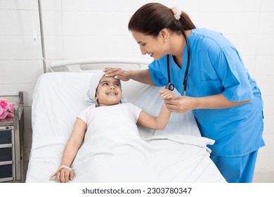 Young indian woman nurse or medical person visit and checkup little girl cancer patient lying on hospital bed undergoing course of chemotherapy. Healthcare concept. - Powered by Shutterstock