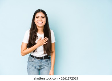 Young Indian Woman On Blue Background Laughs Out Loudly Keeping Hand On Chest.