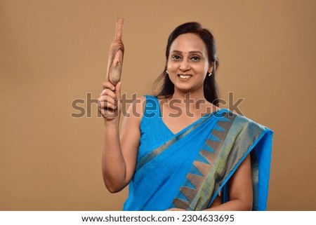 young indian woman in saree holding rolling pin