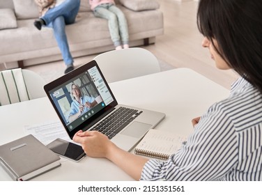 Young Indian Woman Student, Remote Employee Working Online From Home Office Sit At Table Using Laptop Computer Having Virtual Meeting, E Learning, Watching Webinar Class Training. Over Shoulder View