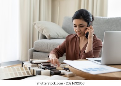 Young Indian woman talk on cell consult client on block or bar sample decorating house. Ethnic female architect or designer speak with customer on smartphone, advise on brick interior design option.