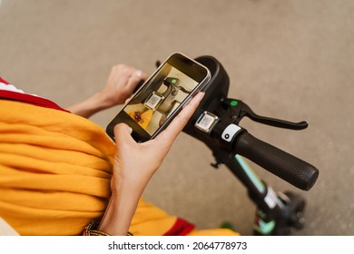 Young Indian Woman Using Cellphone While Standing With Powered Scooter Outdoors