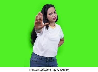 Young Indian Woman Wearing Casual White T-shirt Over Green Studio Isolated Background, Saying No, Doing Stop Sign, Looking Straight In To Camera.