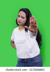 Young Indian Woman Wearing Casual White T-shirt Over Green Studio Isolated Background, Saying No, Doing Stop Sign, Looking Straight In To Camera.