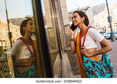 Young Indian Woman Wearing Sari Talking On Cellphone While Standing At City Street