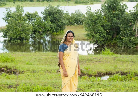 Young Indian woman wearing sari near lake and enjoying the colors of nature.