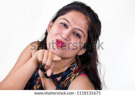 A young Indian women wearing a black sleeveless dress, making funny faces and teasing with naughty expressions , isolated against a white background