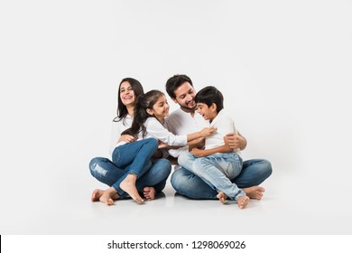 Young Indian/asian Family Sitting Isolated Over White Background. Selective Focus