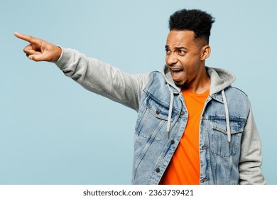 Young indignant sad man of African American ethnicity wear denim jacket orange t-shirt point index finger aside scream isolated on plain pastel light blue background studio portrait. Lifestyle concept - Powered by Shutterstock