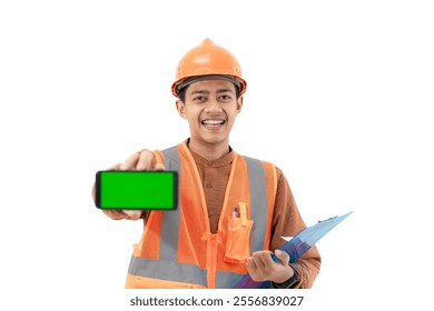 Young Indonesian male construction worker in full safety gear showing green screen of mobile phone to camera, construction and industry advertisement, construction and industry concept, isolated. - Powered by Shutterstock