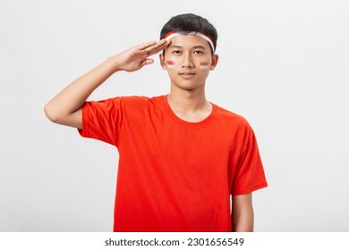 Young Indonesian man saluting flag of Indonesia celebrate independence day 17 August isolated on white background. Dirgahayu 78 Tahun Kemerdekaan Indonesia. - Powered by Shutterstock