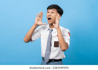 Joven estudiante indonesio de secundaria anunciando información gritando fuerte aislado de fondo azul. Pelajar siswa SMA (Sekolah menengah atas) Indonesia