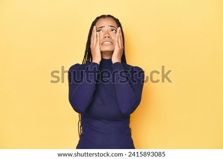 Young Indonesian woman on yellow studio backdrop whining and crying disconsolately.