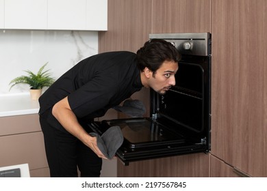 Young inexperienced cooker trying to open the oven but something going wrong. Burnt food and bad smell concept - Shutterstock ID 2197567845
