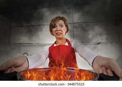 Young Inexperienced Home Cook Woman In Panic With Apron Holding Pot Burning In Flames With Stress And Panic Face Expression In Fire In The Kitchen And Amateur Newbie Rookie Ad Messy Cooking Concept