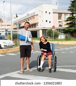 Young injured couple with broken foot and arm coming out of the hospital happy that their insurance paid the medical bills in travel health insurance concept.