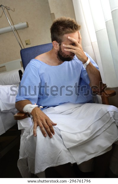 young injured man crying in hospital room\
sitting alone in pain looking negative and worried for his bad\
health condition sitting on chair suffering depression on a dark\
sullen medical background