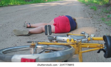 Young Injured Unconscious Caucasian Girl Cyclist Laying On Ground Rural Road After Being Hit By Car