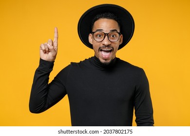 Young Insighted Smart Proactive African American Man 20s Wearing Stylish Black Hat Shirt Eyeglasses Holding Index Finger Up With Great New Idea Isolated On Yellow Orange Background Studio Portrait