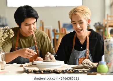 A young instructor teaching an LGBT teenage boy to do DIY handcrafted ceramic in art workshop, art and craft academy concept. - Powered by Shutterstock