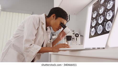 Young intelligent  female doctor looking in a microscope