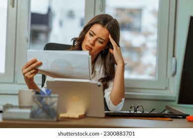 Young intern is having difficulties with her new assignment, she looks tired and confused as she looks at the chart