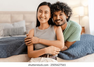 Young interracial couple embraces in their cozy bedroom, radiating love and joy, showcasing their multicultural relationship. Love concept - Powered by Shutterstock