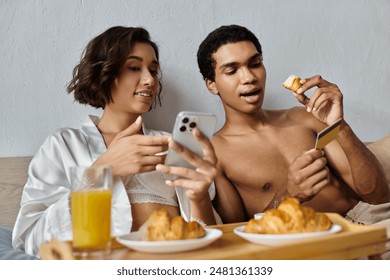 A young interracial couple enjoys a cozy morning together in their bedroom, sharing a meal and spending quality time together. - Powered by Shutterstock