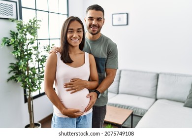 Young Interracial Couple Expecting A Baby, Touching Pregnant Belly With A Happy And Cool Smile On Face. Lucky Person. 