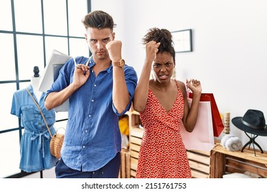 Young Interracial Couple Holding Shopping Bags At Retail Shop Angry And Mad Raising Fist Frustrated And Furious While Shouting With Anger. Rage And Aggressive Concept. 