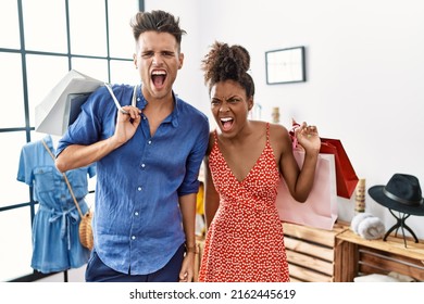 Young Interracial Couple Holding Shopping Bags At Retail Shop Angry And Mad Screaming Frustrated And Furious, Shouting With Anger. Rage And Aggressive Concept. 