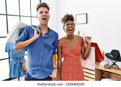 Young Interracial Couple Holding Shopping Bags At Retail Shop Angry And Mad Screaming Frustrated And Furious, Shouting With Anger. Rage And Aggressive Concept. 