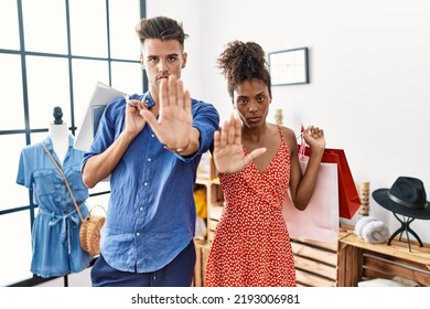 Young Interracial Couple Holding Shopping Bags At Retail Shop Doing Stop Sing With Palm Of The Hand. Warning Expression With Negative And Serious Gesture On The Face. 