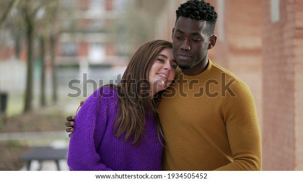 Young interracial couple kissing holding hands\
walking outside together