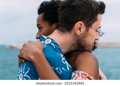 Young interracial couple is sharing a tender moment, embracing each other tightly with the ocean as their backdrop. They are finding solace and strength in their love. - Powered by Shutterstock